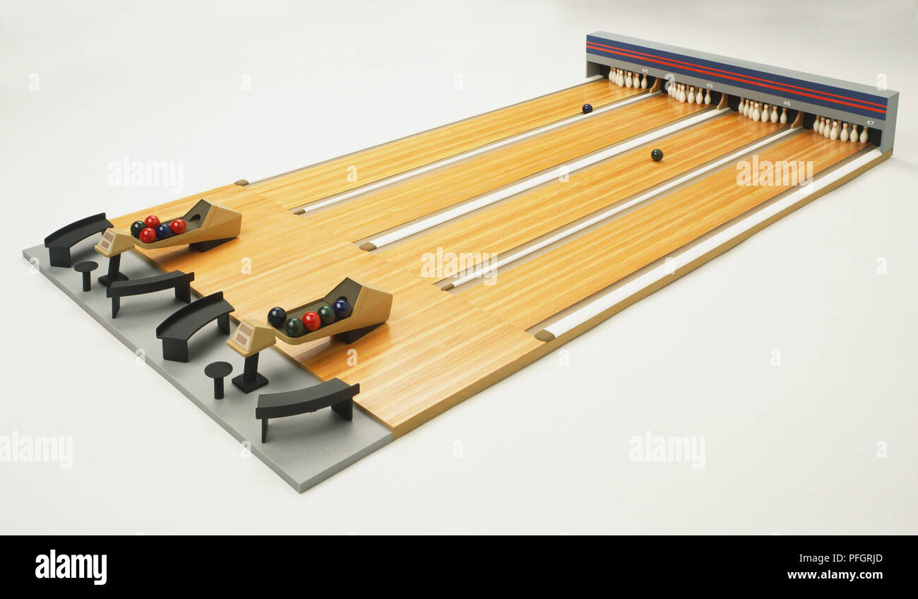 Bowling balls roll down the lanes of a model bowling alley with four