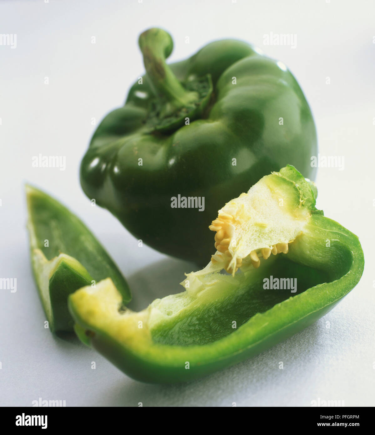 Whole green pepper and separate slices showing seeds. Stock Photo