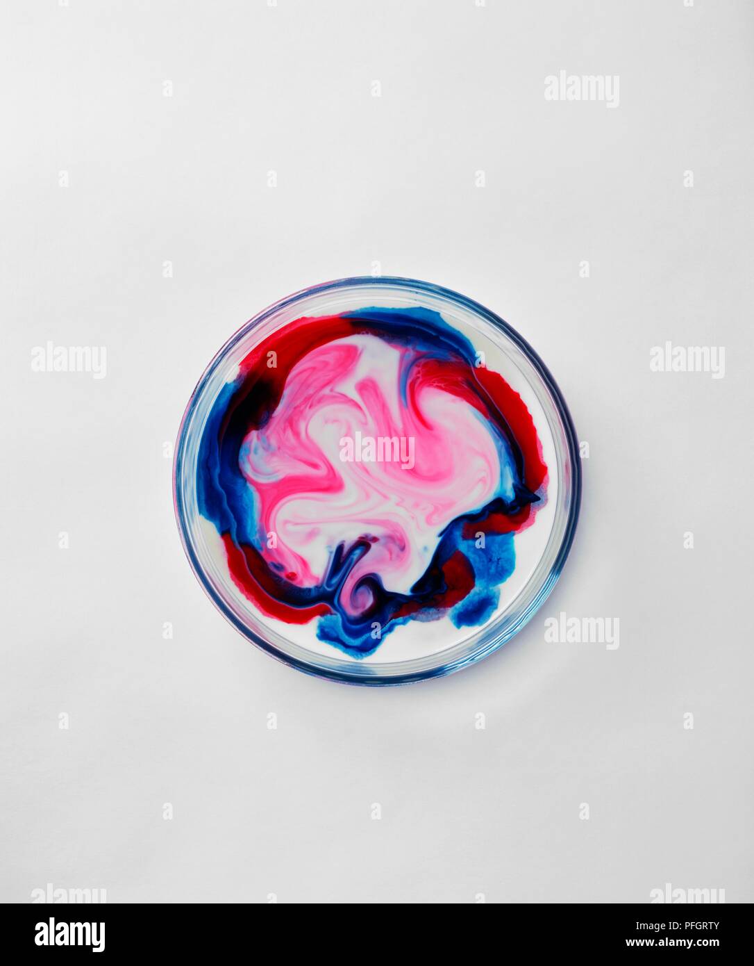Blue and red food colouring swirling and mixing together on surface of