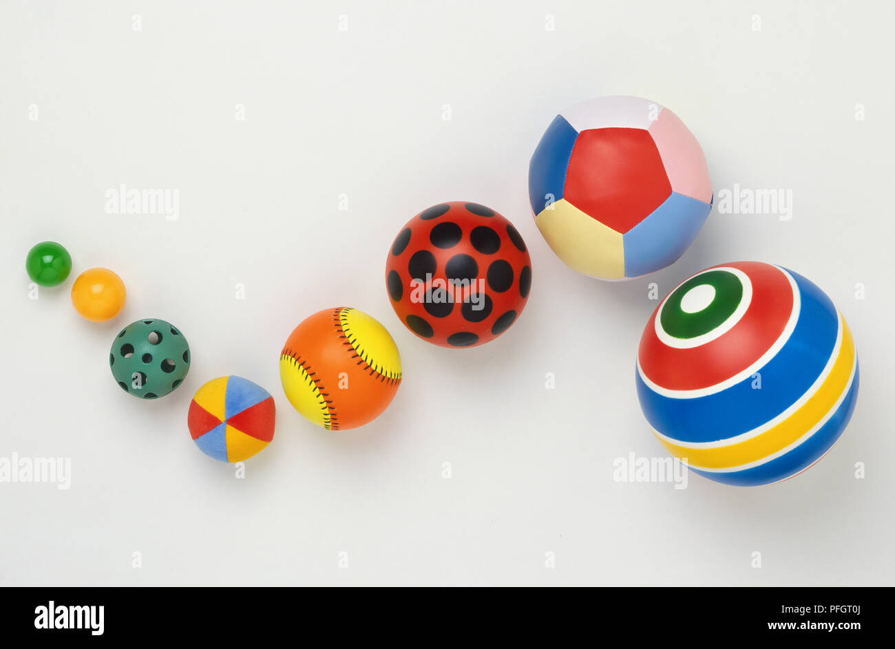 Eight colourful balls of different patterns and sizes, arranged in snake-like shape. Stock Photo