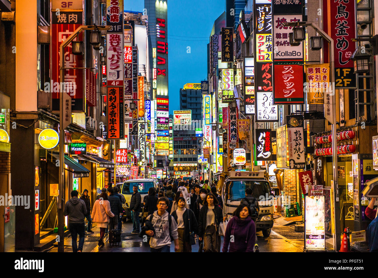 Busy street at night in Shinjuku, Tokyo, Japan, with many neon signs in Japanese Stock Photo