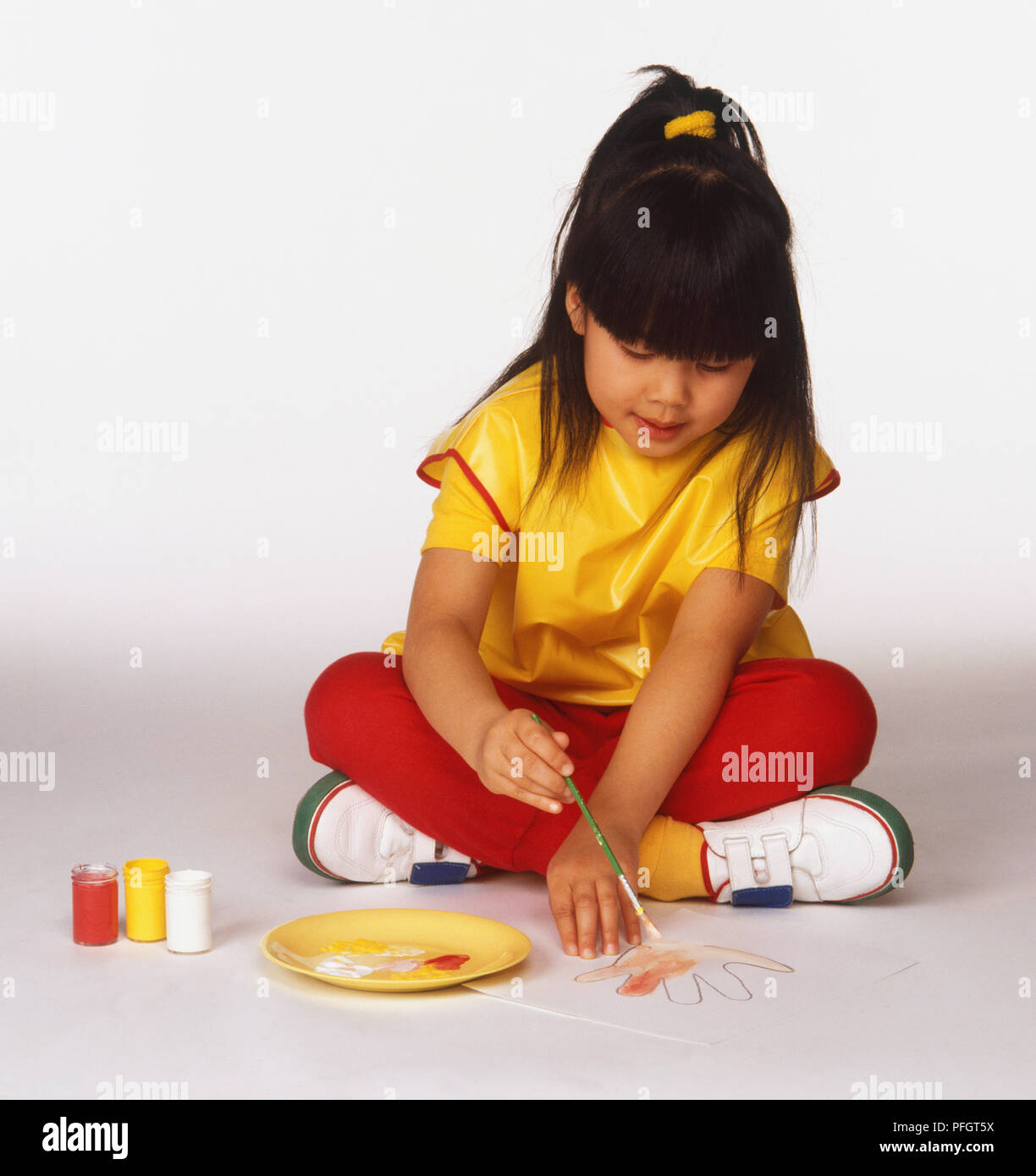 Young girl, with long, brown hair, drawing round her hand and colouring in Stock Photo