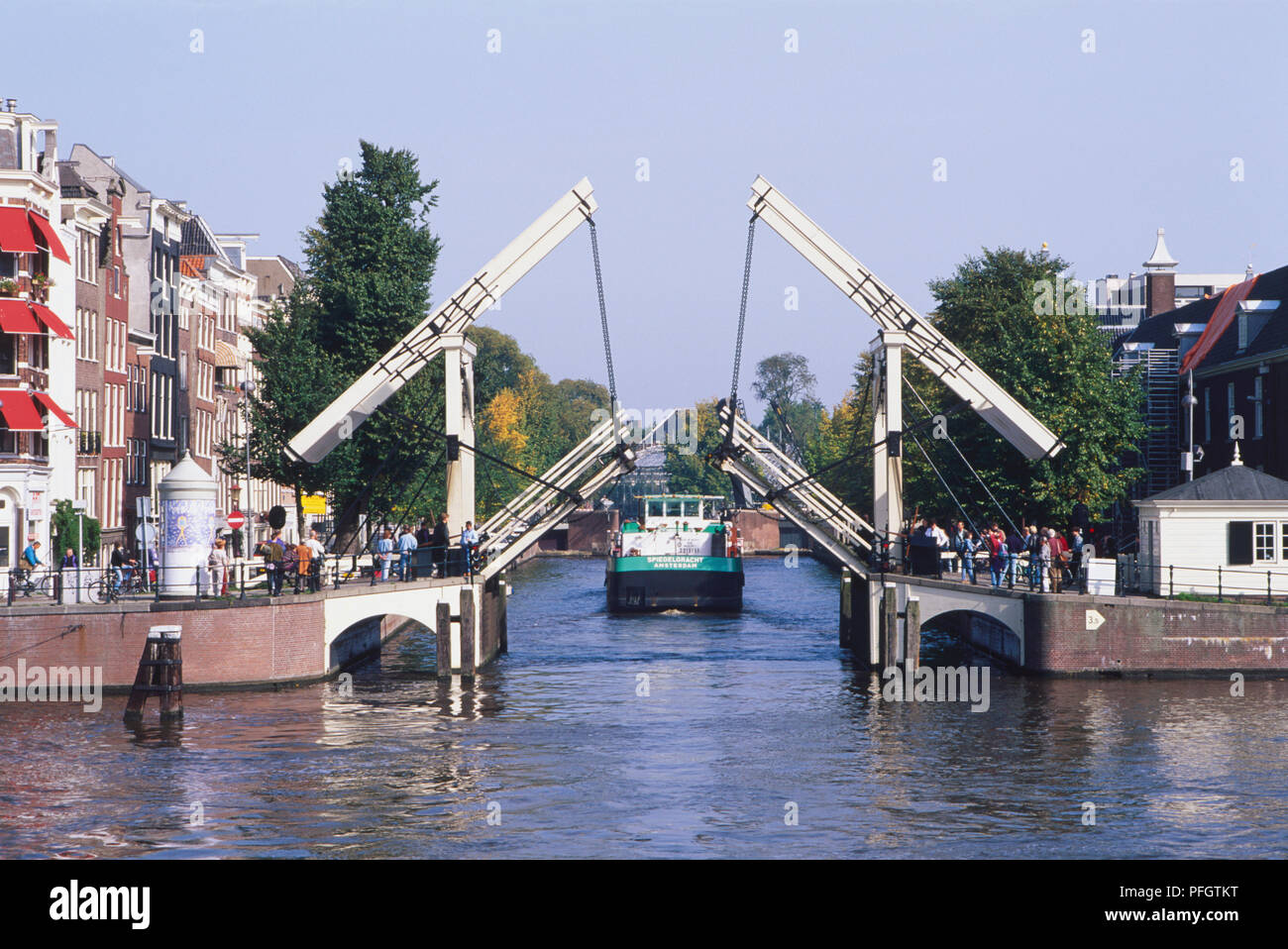 Holland, Amsterdam traditional lift bridge on a canal with a boat passing through. Stock Photo