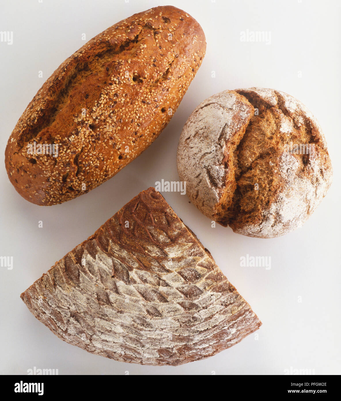 Rustic breads, including triangular chunk of rye bread (Hausbrot), round, crusty loaf of wholemeal bread (Vollkorn-Bauernbrot) and loaf of multi-grain bread (Siebenkornbrot) sprinkled with sesame seeds, view from above Stock Photo