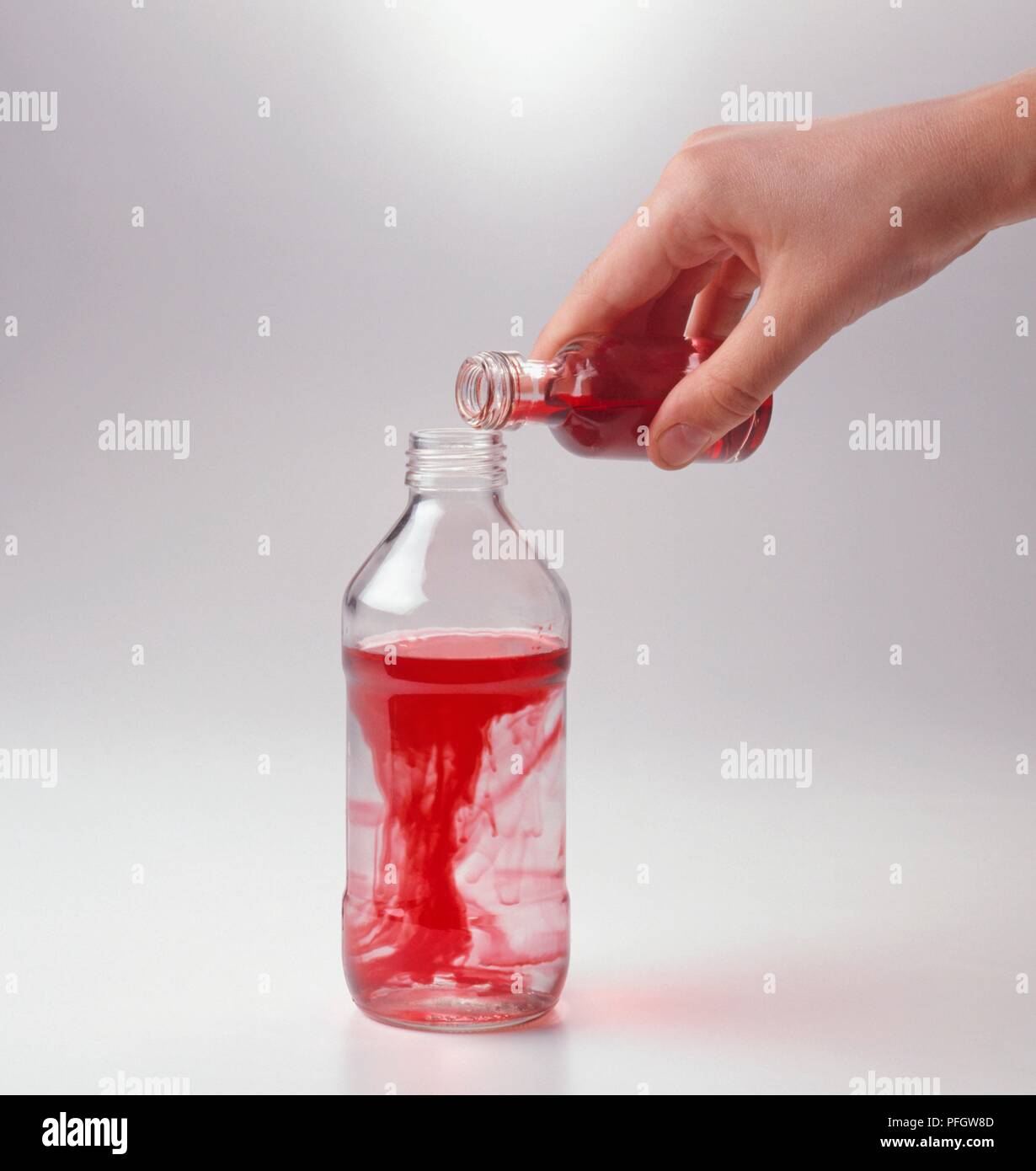 Hand pouring red food colouring into bottle of water Stock Photo Alamy