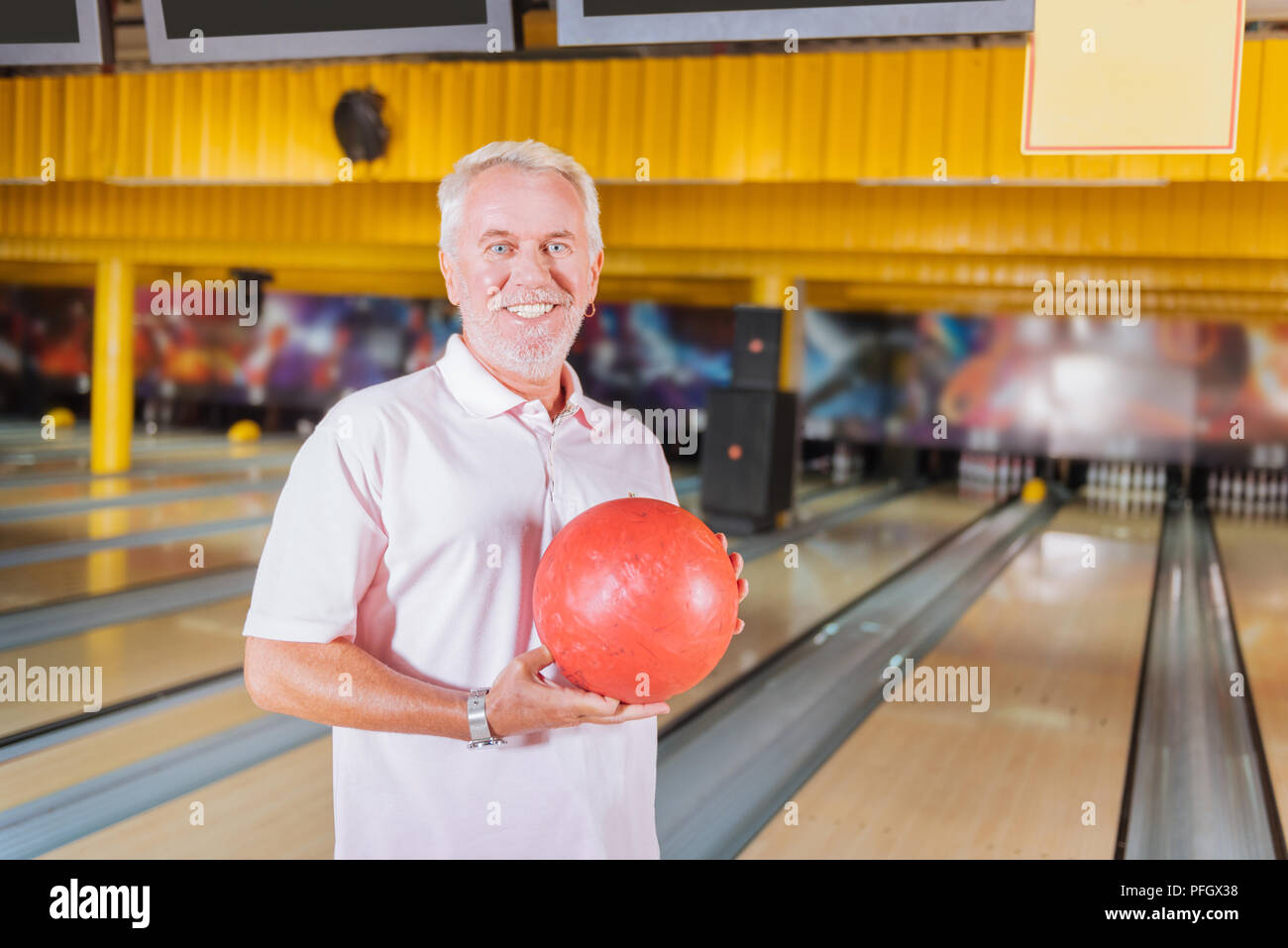 Joyful happy aged man holding a bowling ball Stock Photo