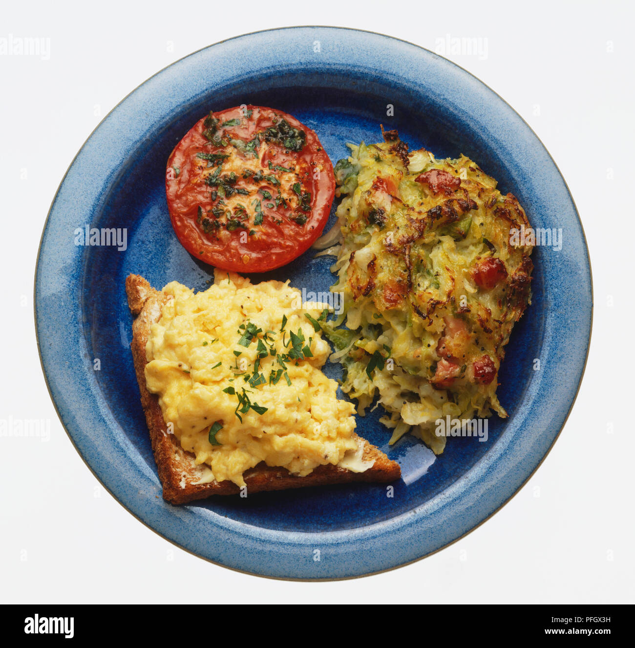 Bubble and squeak, fried eggs on toast and a slice of tomato, served on