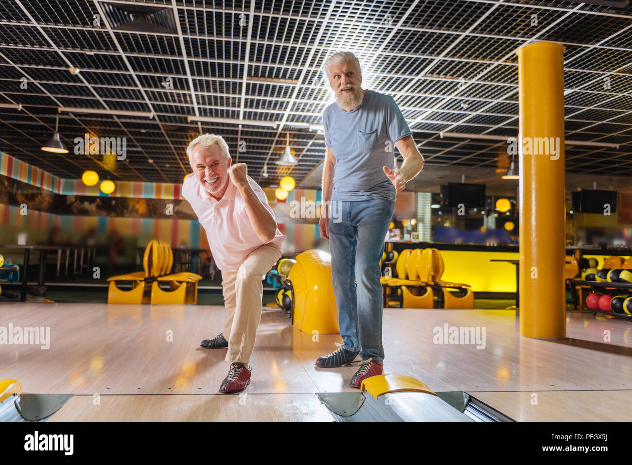 Positive nice elderly men feeling happy in the bowling club Stock Photo