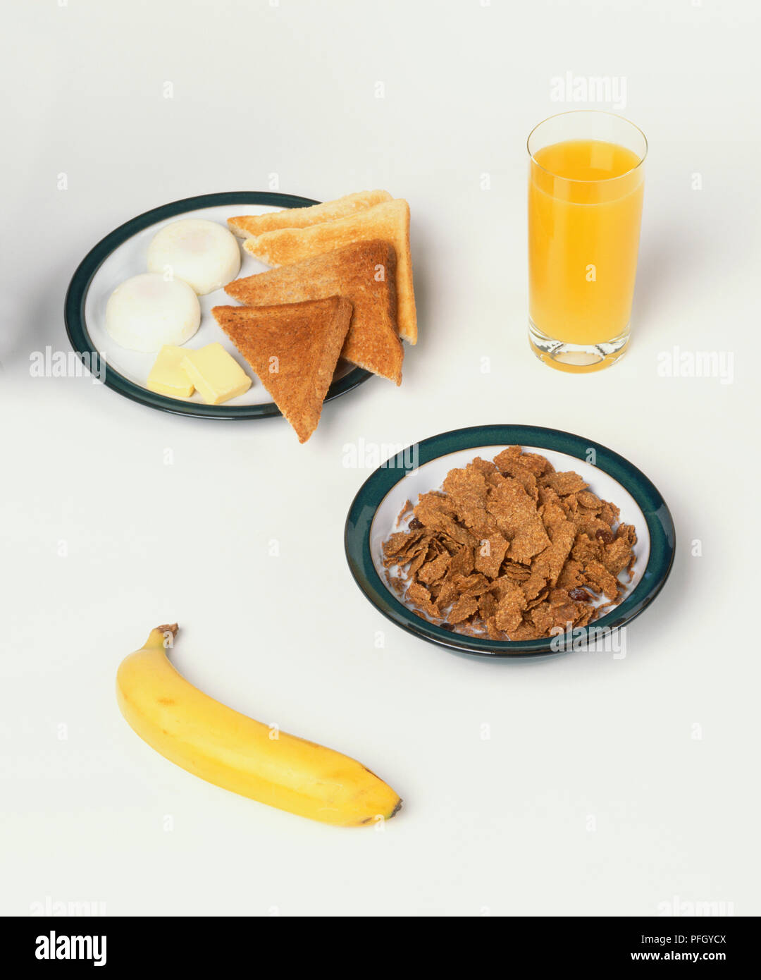 A healthy breakfast of poached eggs, toast, cereal, banana and glass of