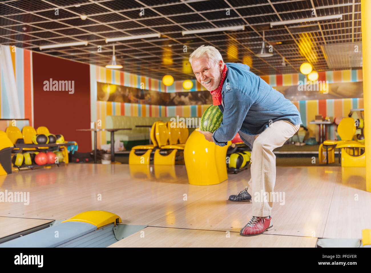 Cheerful aged man playing bowling with a watermelon Stock Photo