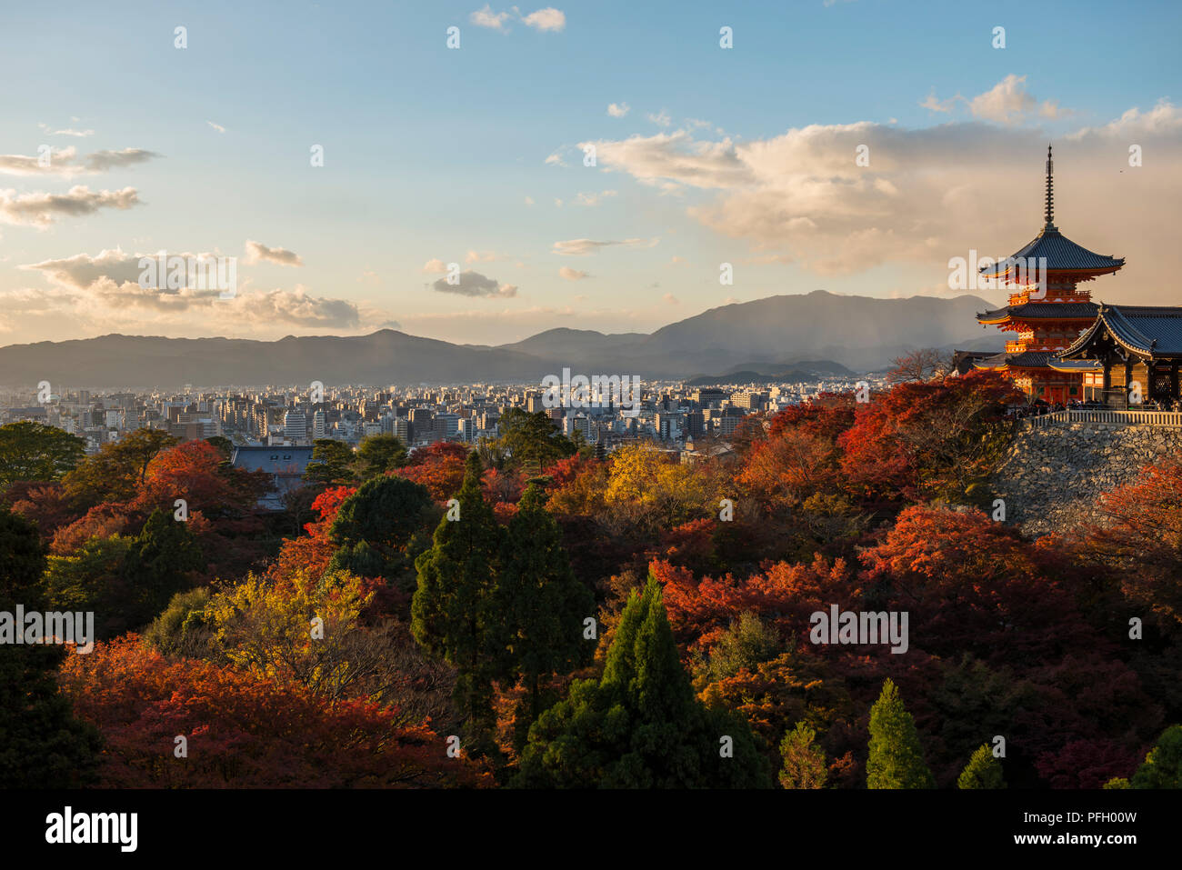 Late afternoon view of the Kyoto city skyline from Kyomizu-Dera Temple in Kyoto, with the temple and autumn trees in the foreground. Kyoto, Japan Stock Photo