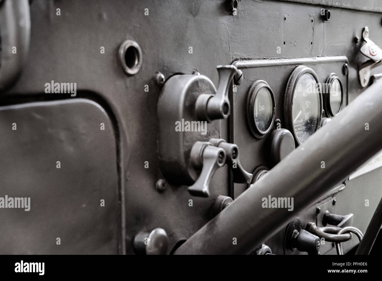 Close-up, shallow focus of a restored Korean War era US Army Jeep showing its steering column, dials and switch gear. Painted in olive drab. Stock Photo