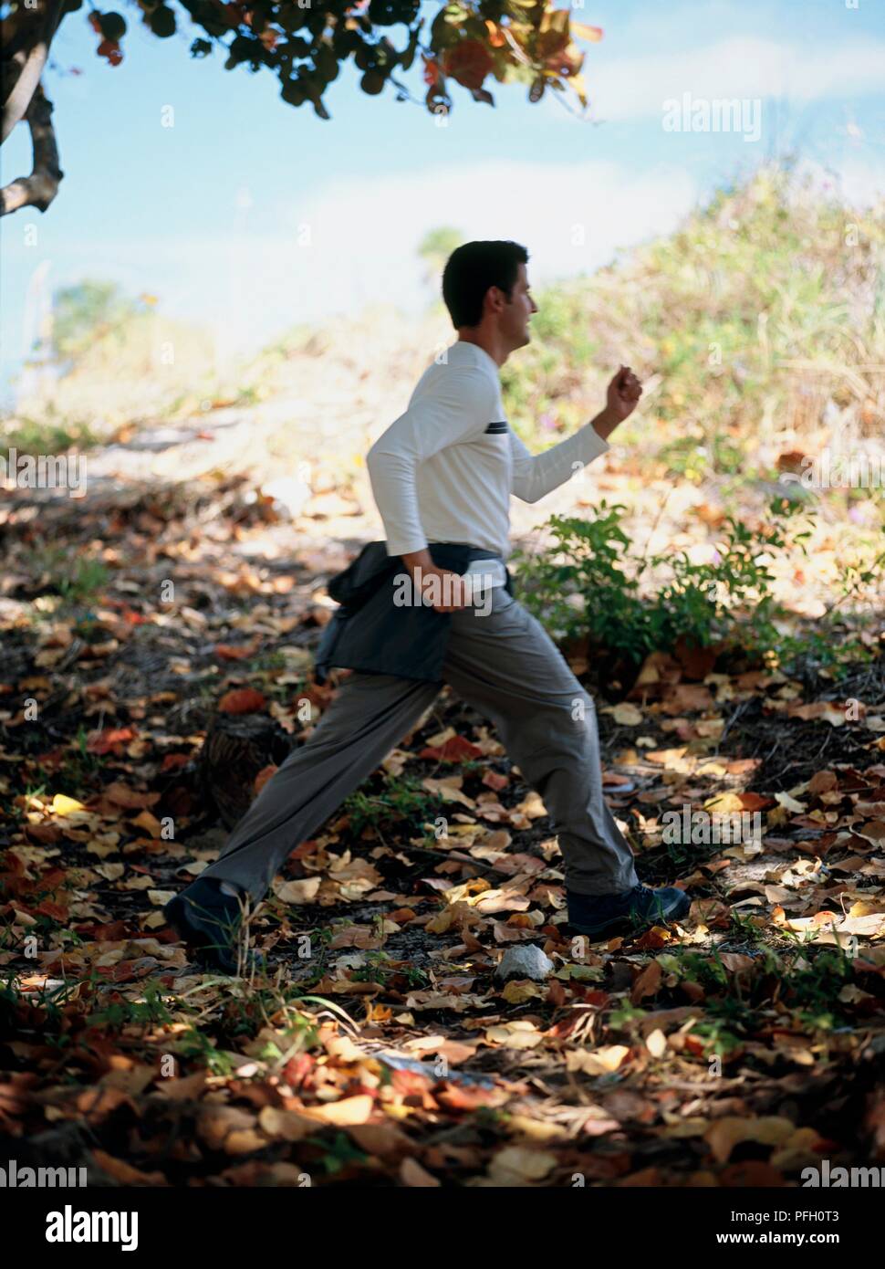 Man jogging through woodland area, side view Stock Photo