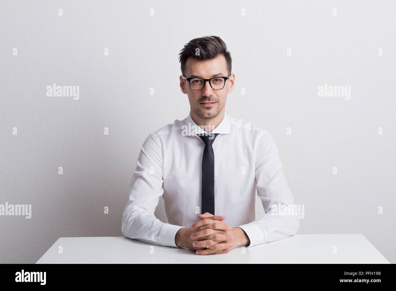 Portrait of a young man with glasses and white shirt in a studio on a ...