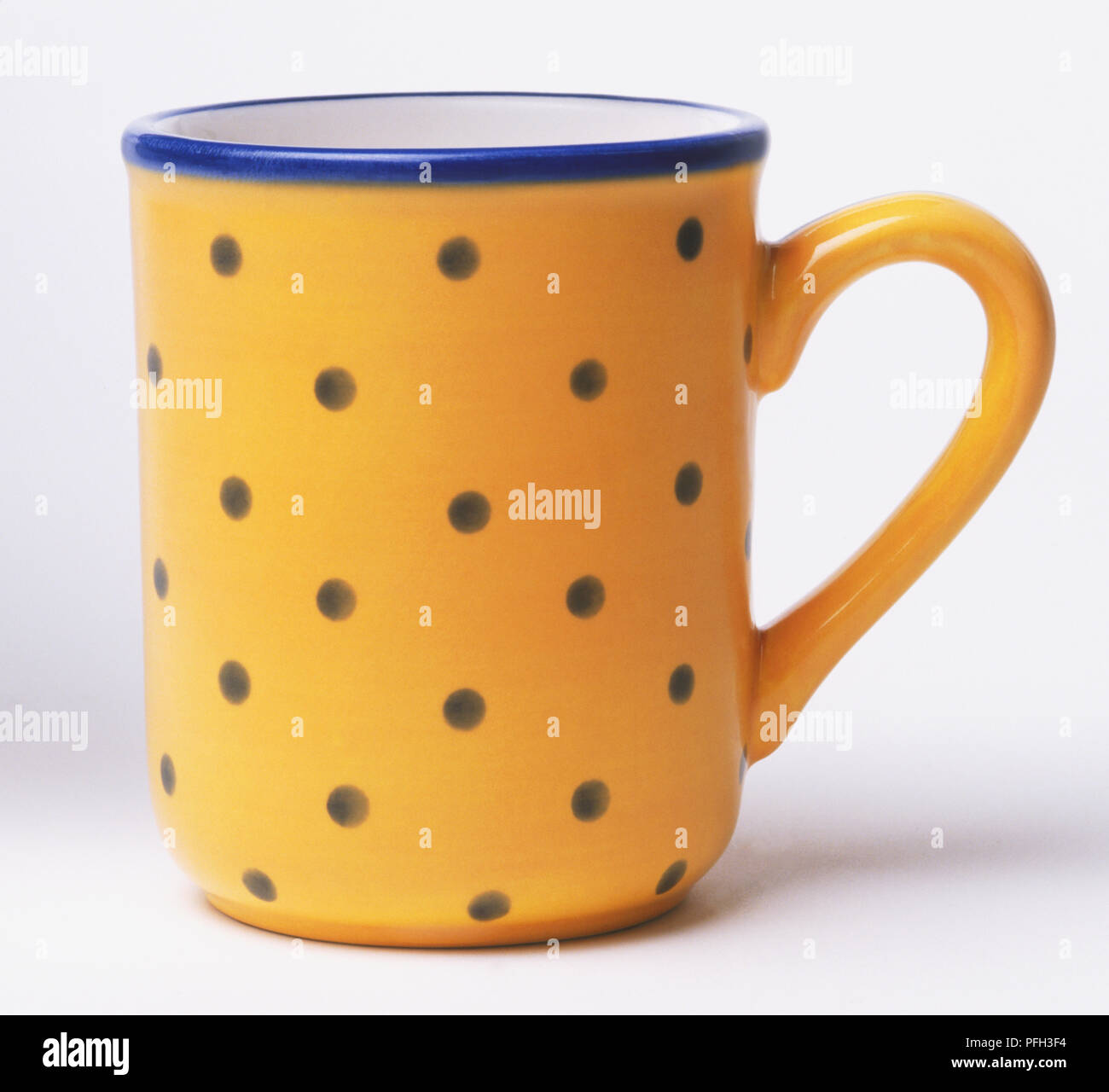 Yellow mug with a pattern of blue dots, front view Stock Photo