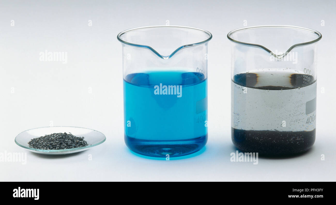 Solid metallic copper at bottom of glass beaker containing Zinc sulphate solution, beaker of blue copper sulphate solution, and zinc metal shavings on watchglass Stock Photo