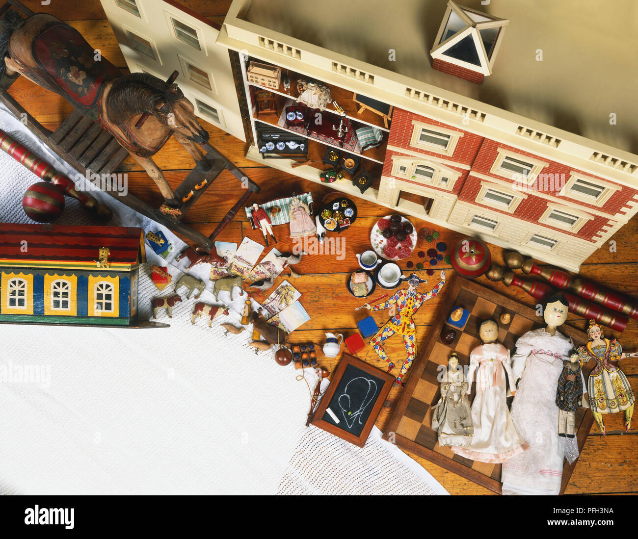 Collection of old-fashioned toys, including a dollhouse, dolls, rocking horse, wooden chess board and miniature blackboard, view from above Stock Photo