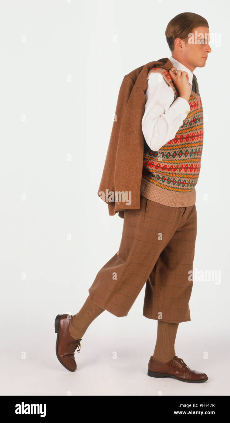 Man wearing wide trousers falling just below the knee, and matching tweed jacket over his shoulder Stock Photo