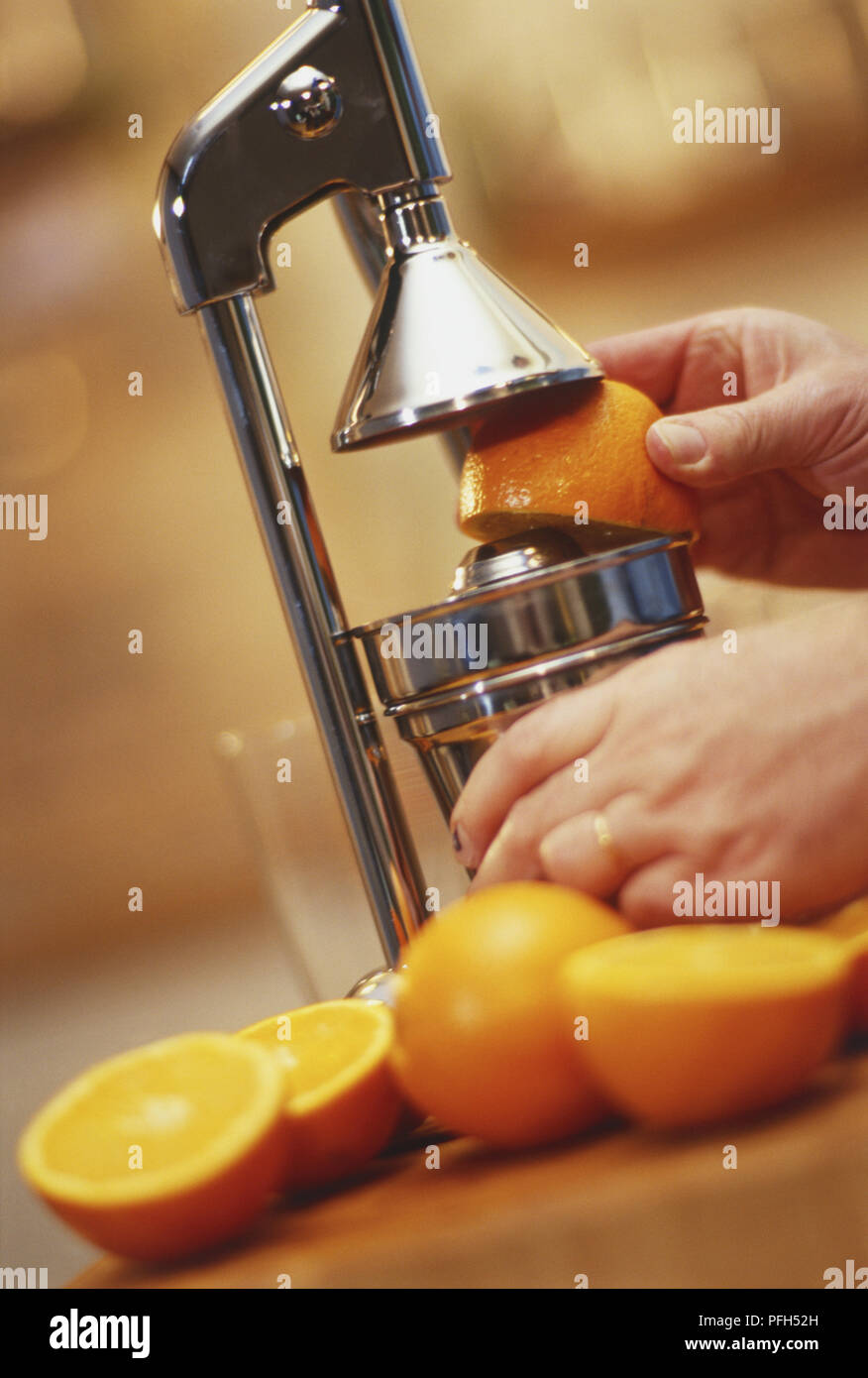 Hand holding half an orange in a juicer Stock Photo Alamy