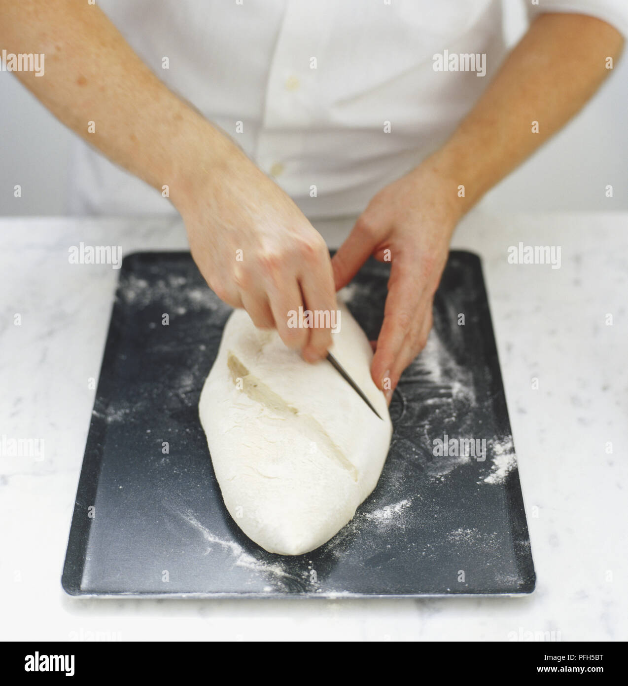 Slashing the upper surface of a bread dough Stock Photo