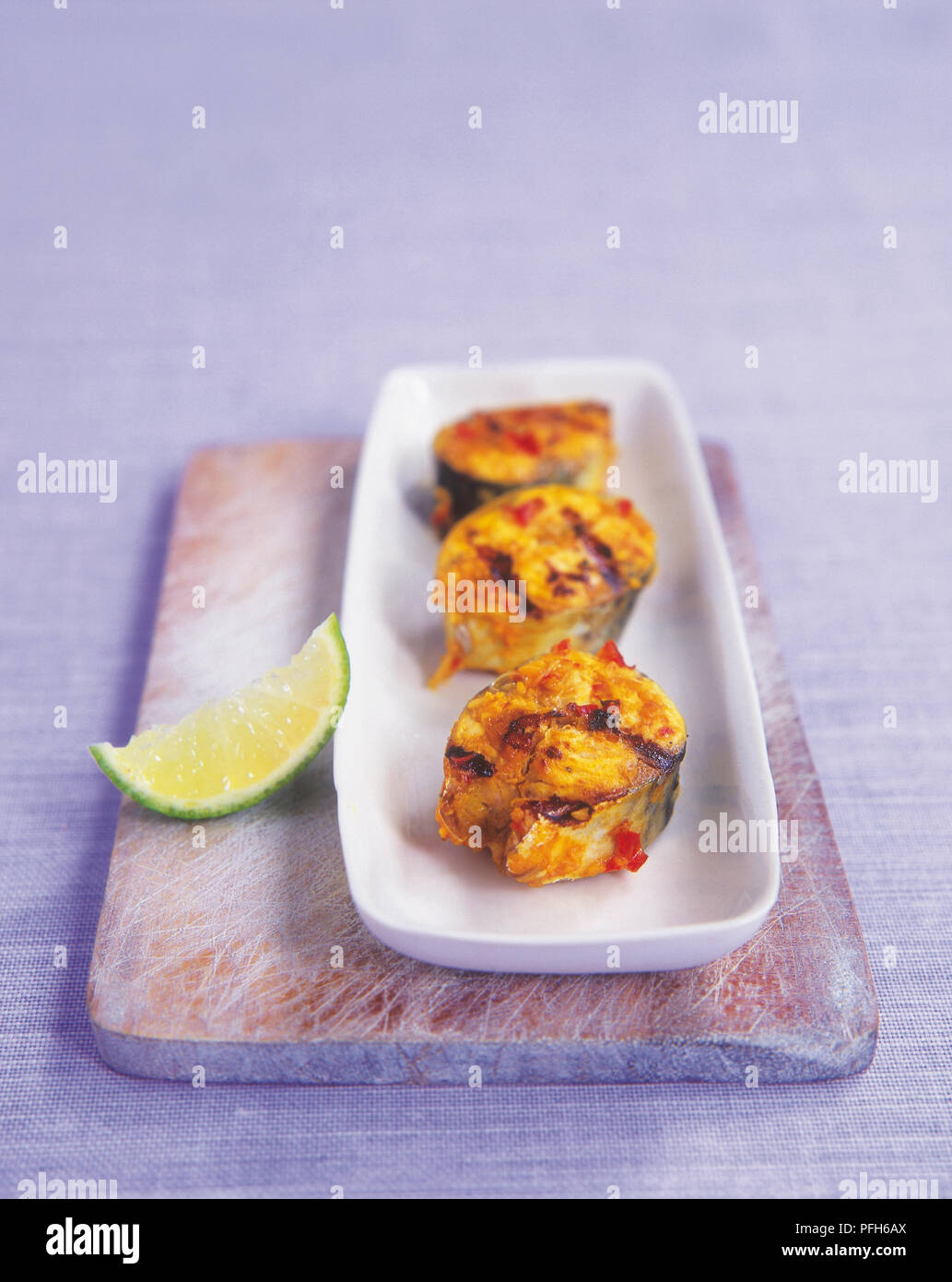 Marinated grilled mackerel (Ikan panggang), three fish steak in rectangular serving dish Stock Photo