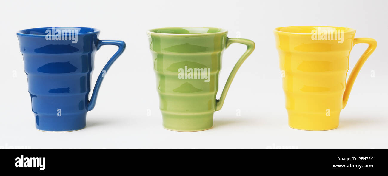 Three funnel shaped coffee or tea mugs, blue, green and yellow Stock Photo