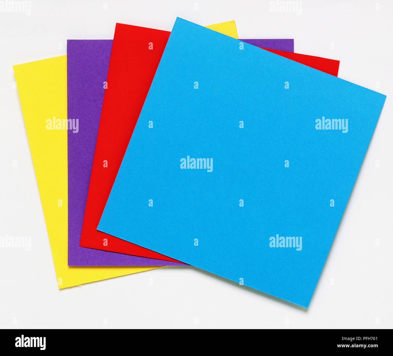 Square pieces of card, blue, red, purple and yellow Stock Photo