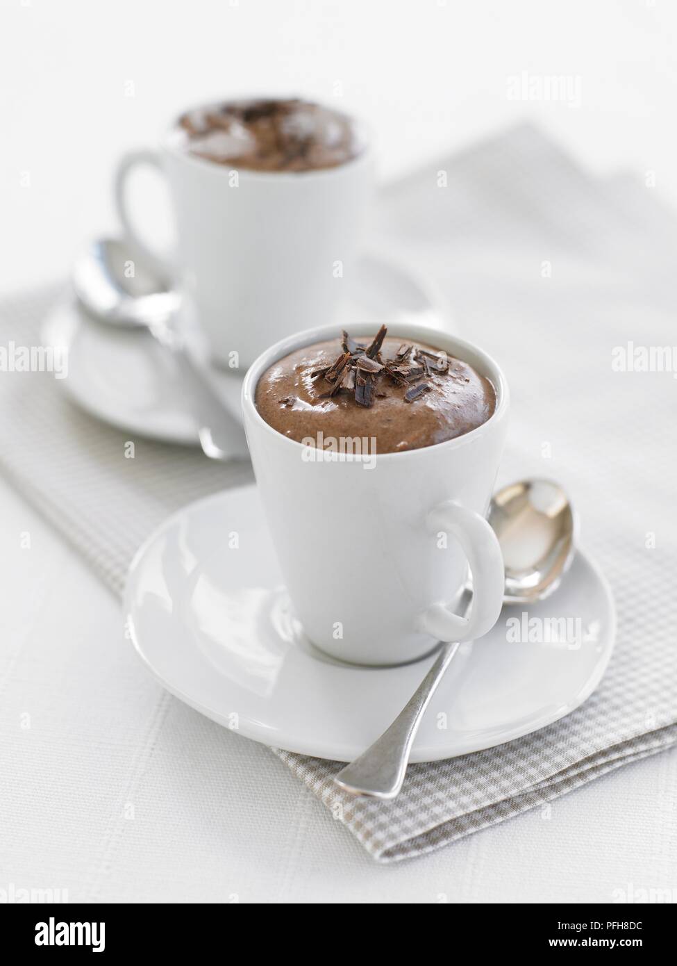 Two portions of chocolate mousse, served in mugs, with spoons, close-up Stock Photo