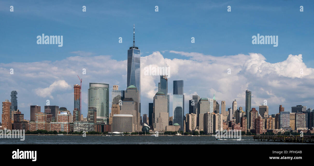 View of the NYC skyline from Harborside in Jersey City, NJ. The skyscrapers are highlighted against a backdrop of clouds. Stock Photo