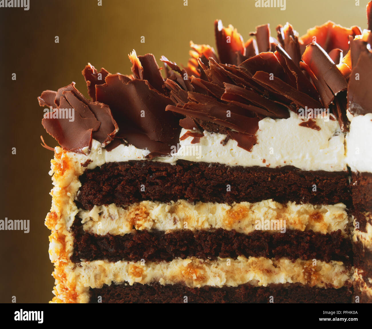 Cross-section of cream layer-cake decorated with chocolate curls and nuts,  close up Stock Photo - Alamy