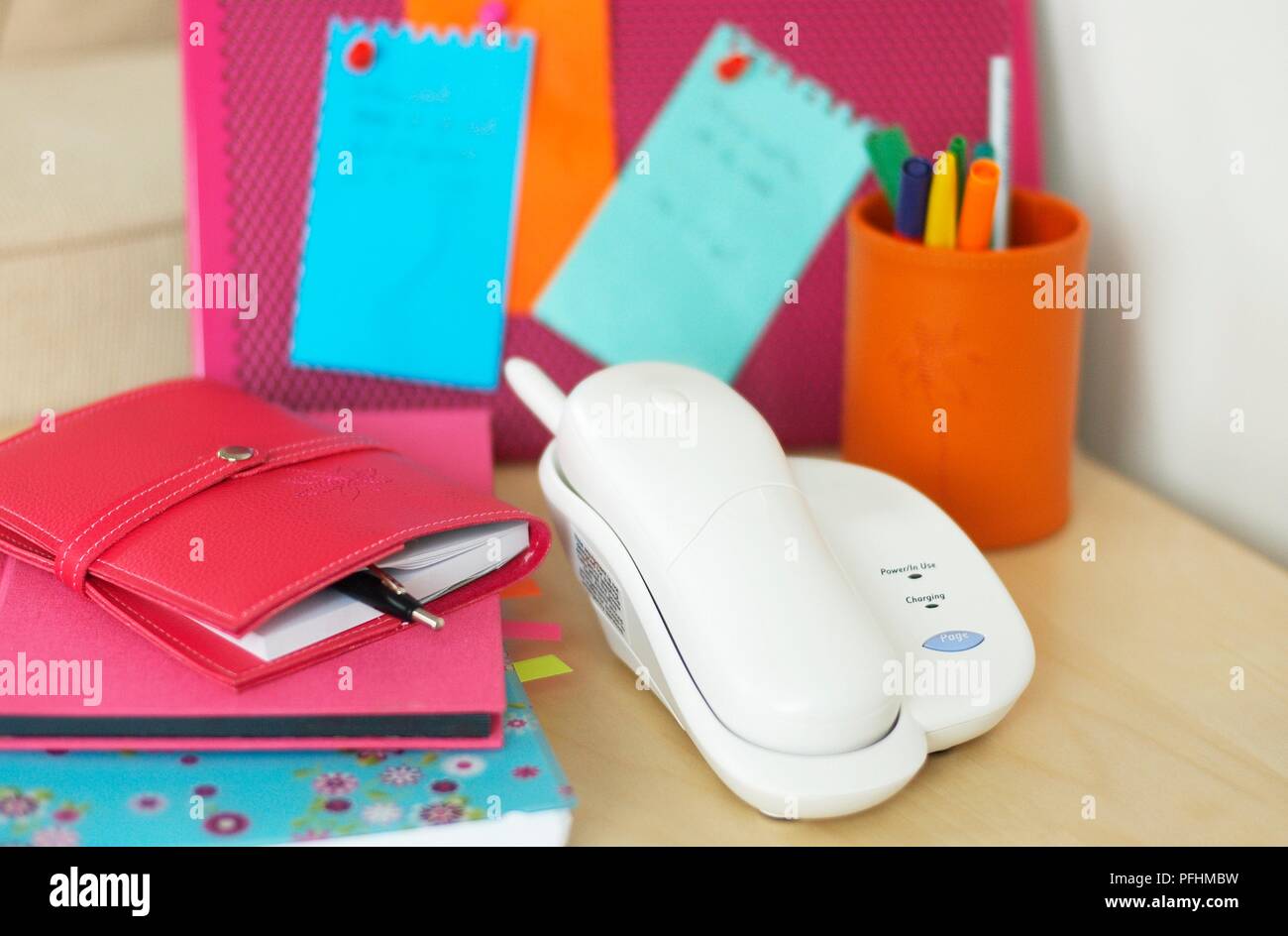 Various items on desk, including telephone, personal organiser, pens, notes on pinboard Stock Photo