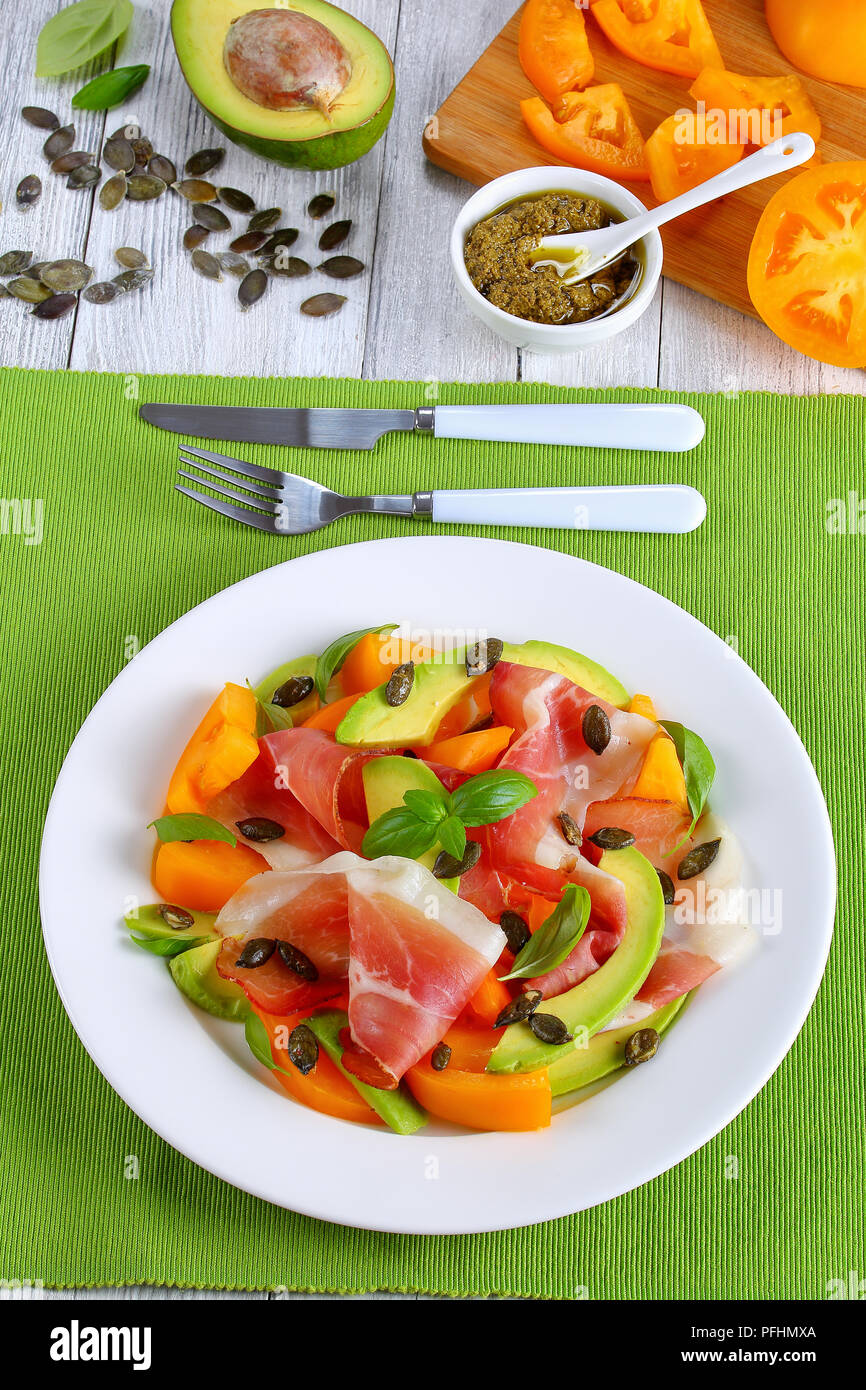 delicious healthy salad with prosciutto, yellow tomato wedges, avocado