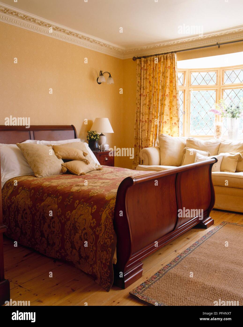 Bedroom with double sleigh bed and cream coloured sofa Stock Photo