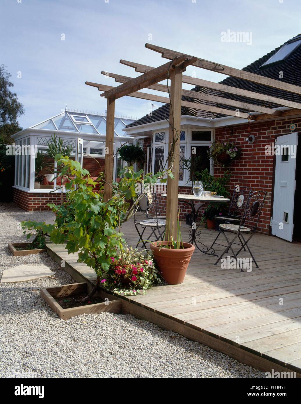Decked patio with table and chairs under pergola Stock Photo Alamy