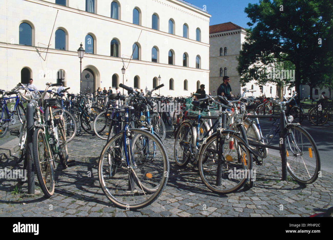 Germany, Bavaria, Munich, large group of bicycles chained to metal posts in bicycle street parking. Stock Photo