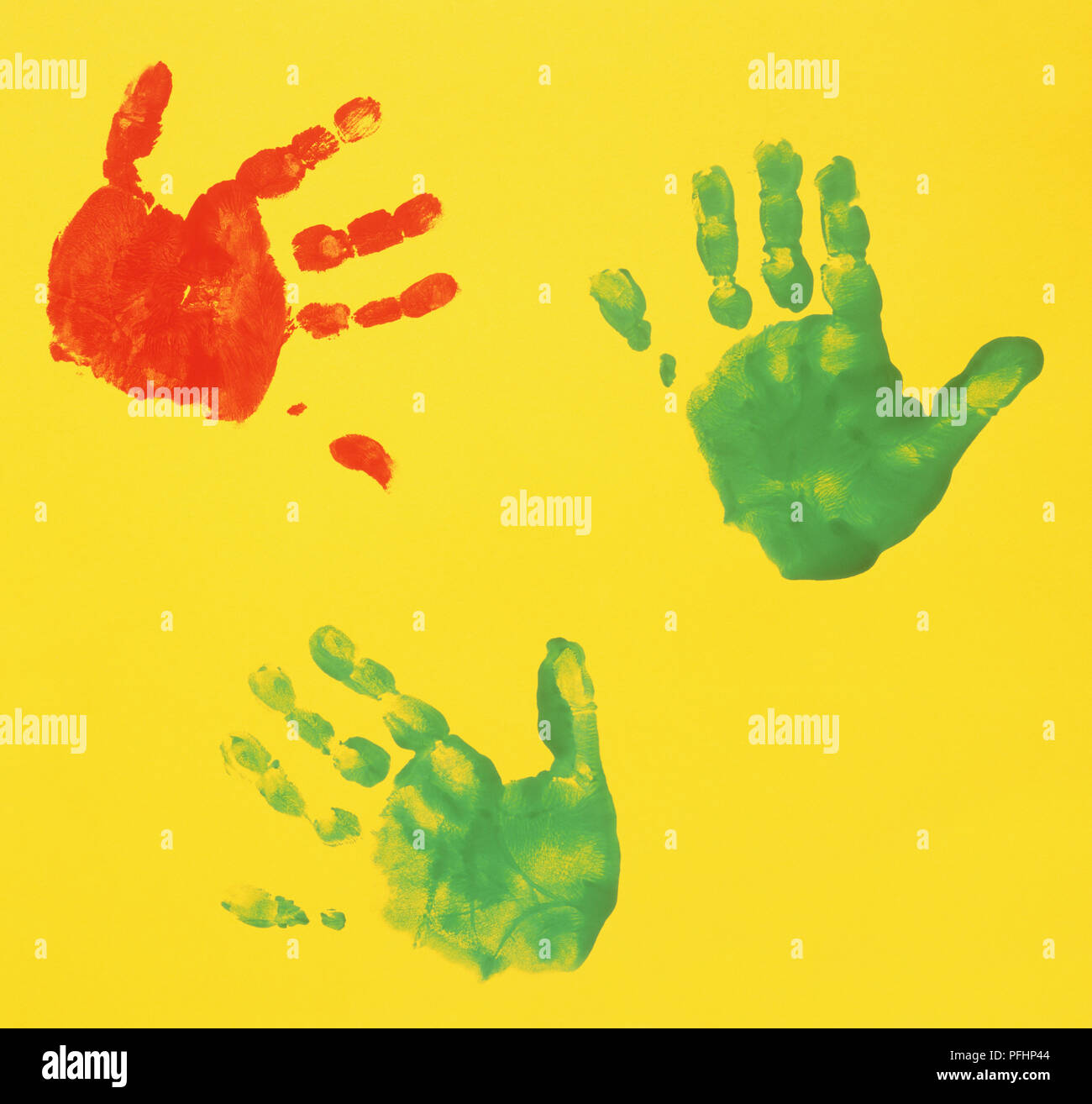 Green and red hand prints on yellow paper Stock Photo