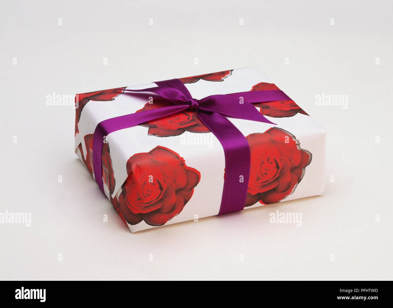 Wrapped Present Front View Present wrapped in paper with red rose pattern and purple ribbon, front ...