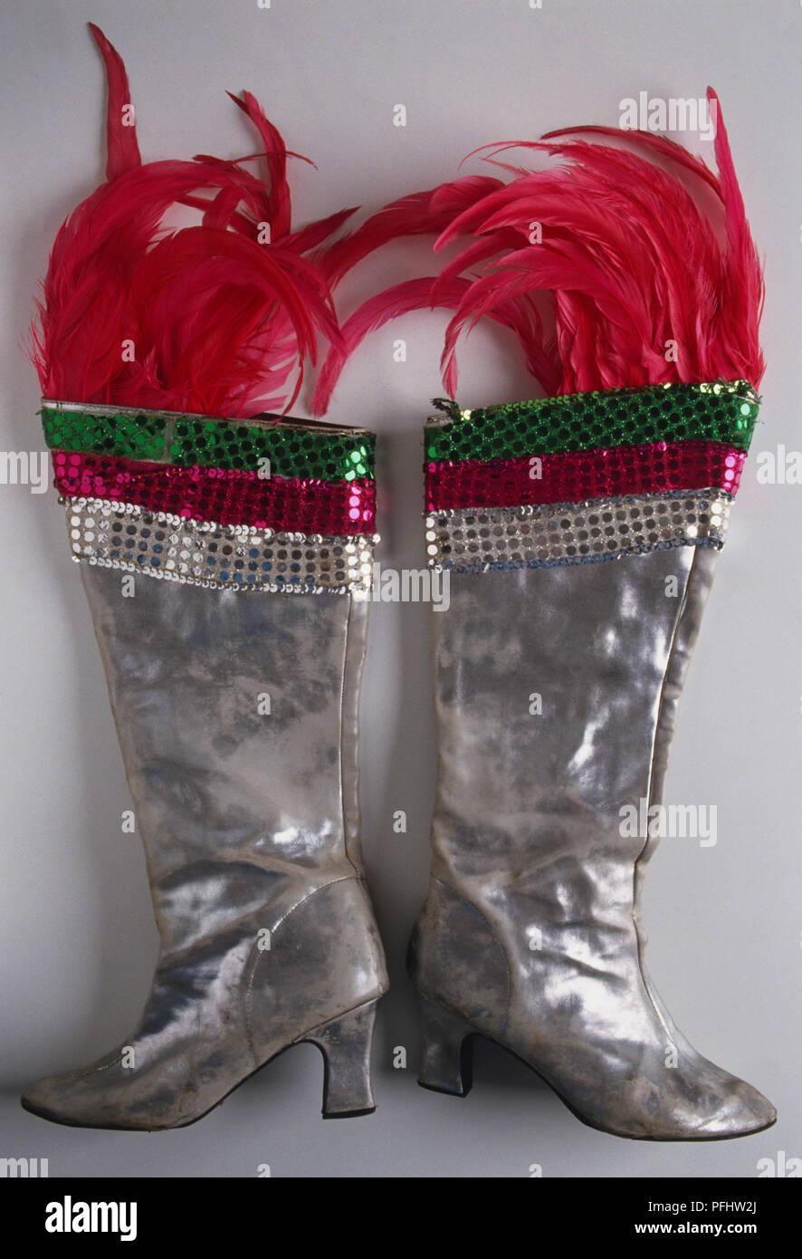 Heeled silver boots decorated with colourful sequins and pink feathers, front view Stock Photo