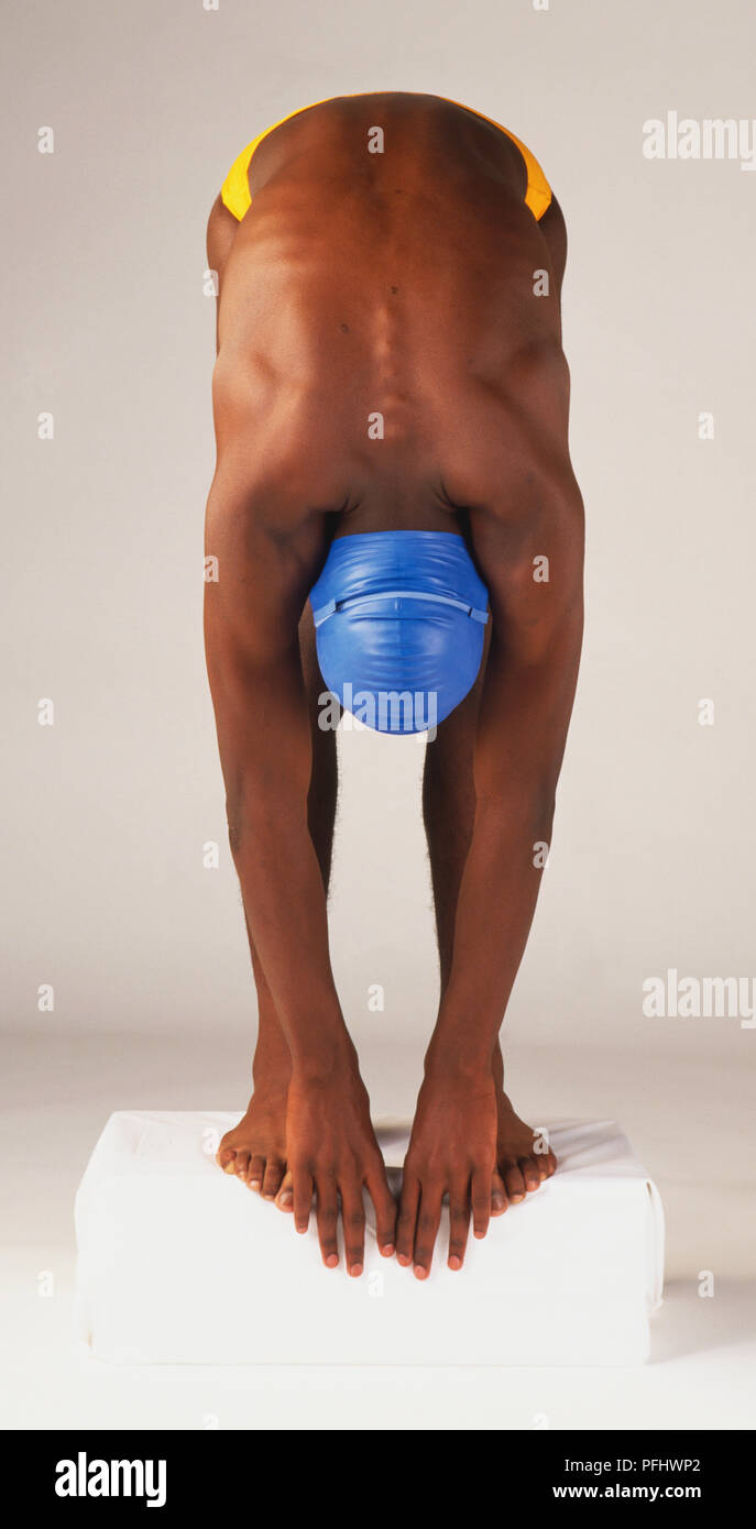 Teenage boy in yellow swimming trunks and blue cap bending all the way  forward in diving position, front view Stock Photo - Alamy