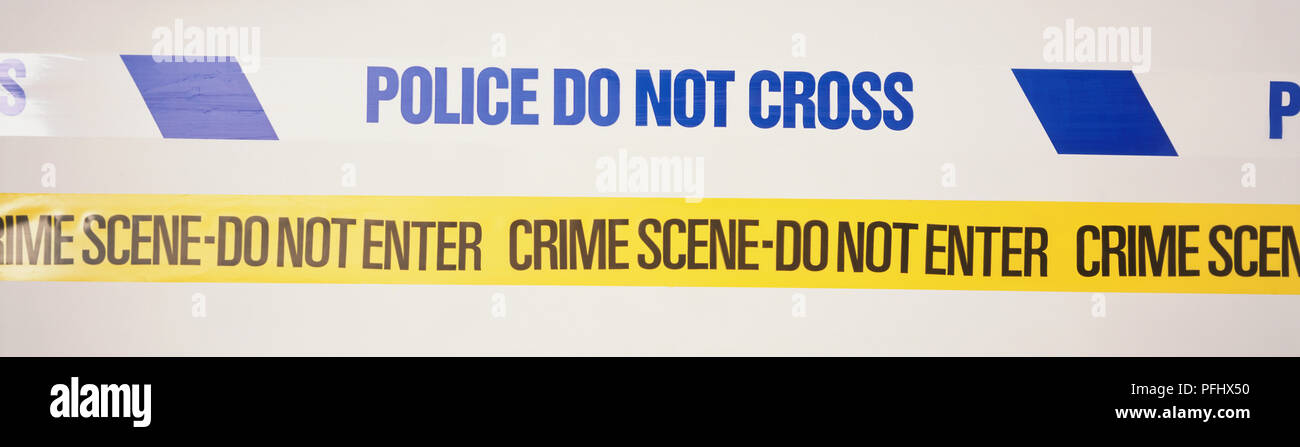 Police area-sealing tapes, one printed with the caption 'police do not cross' and the other 'crime scene do not enter', front view. Stock Photo
