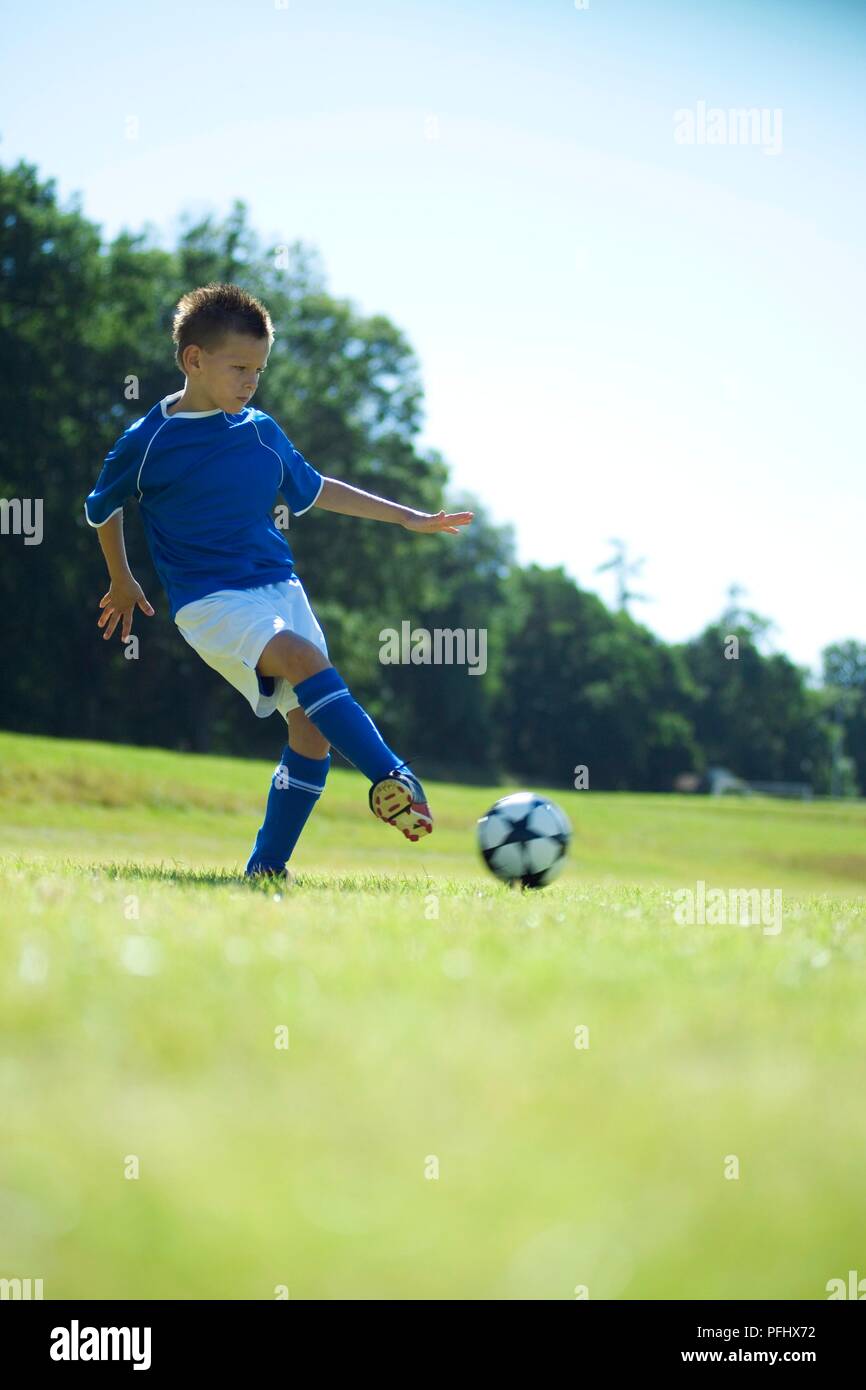 Boy in blue football shirt performing a side foot pass Stock Photo Alamy