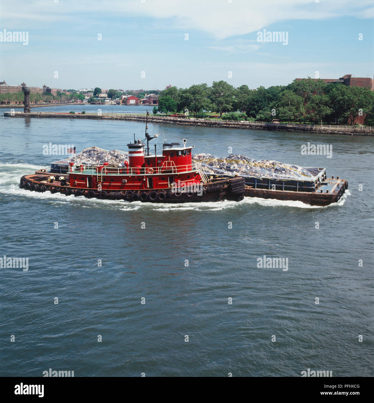 Tug boat with single garbage barge on lake, side view. Stock Photo