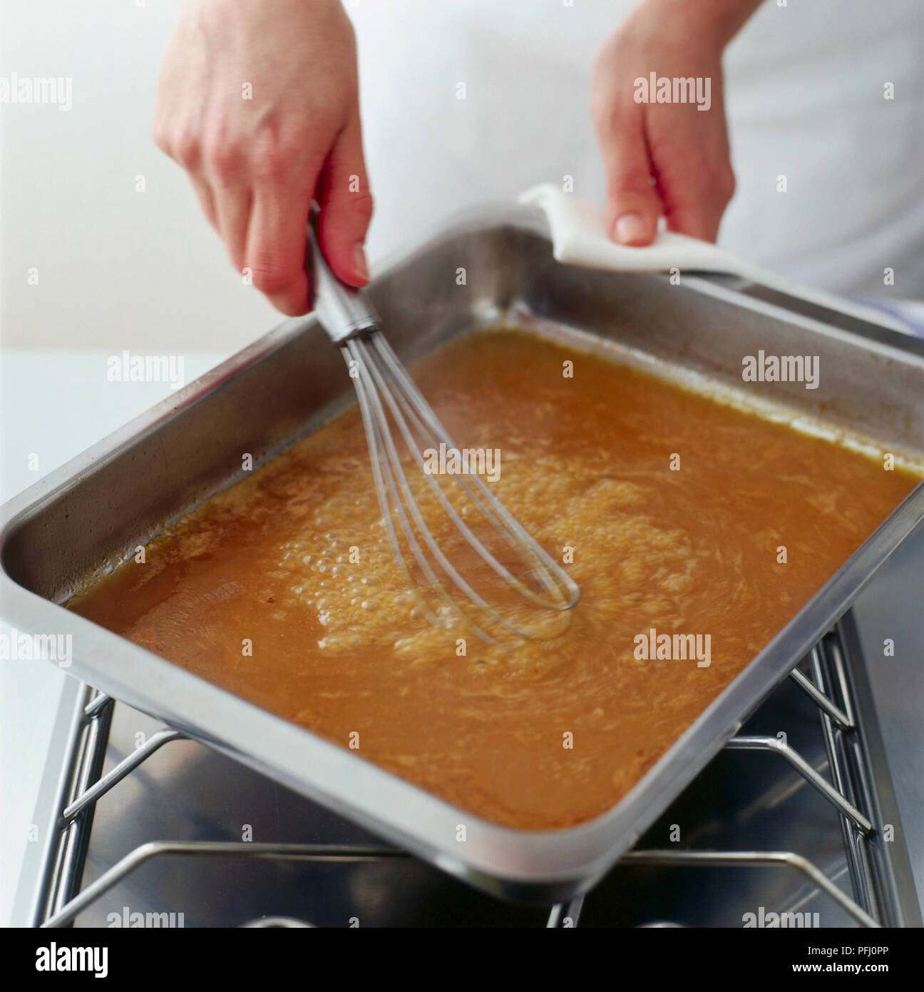 Chicken gravy heated in roasting pan over hob being whisked, high angle view Stock Photo Alamy