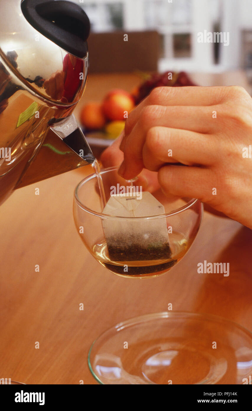 Hand pouring boiling water onto a teabag Stock Photo Alamy