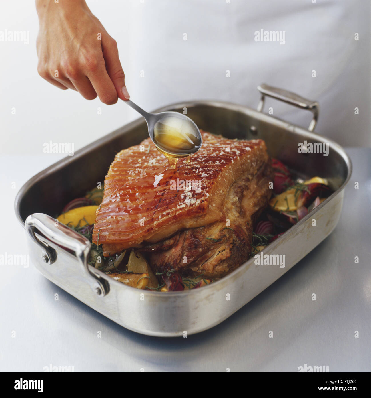 Spooning meat juice over roasted shoulder of pork Stock Photo Alamy