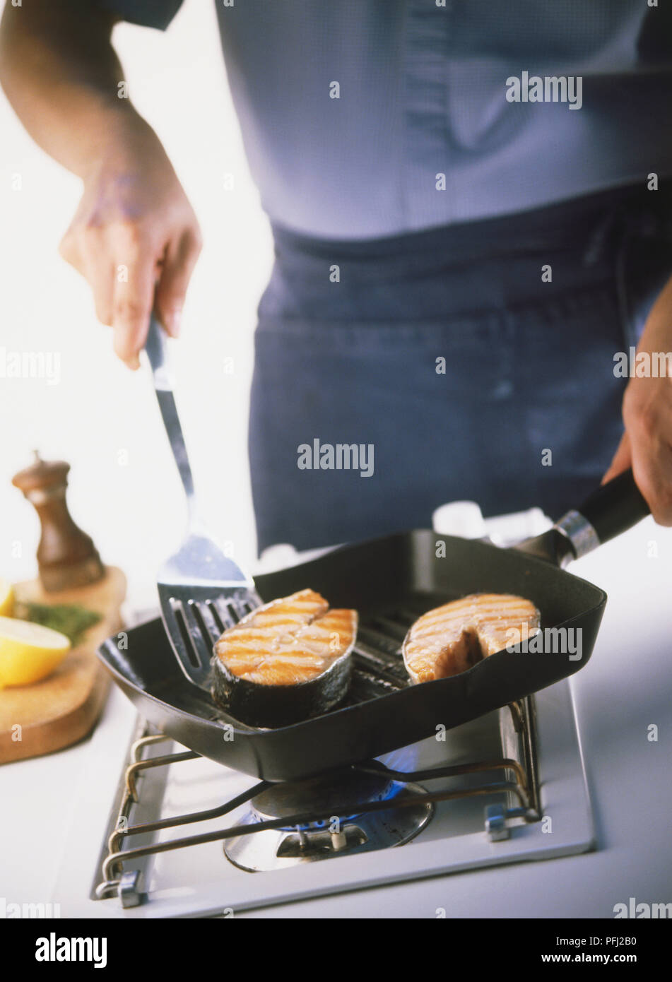 Cooking two salmon steaks in griddle pan on gas stove Stock Photo Alamy