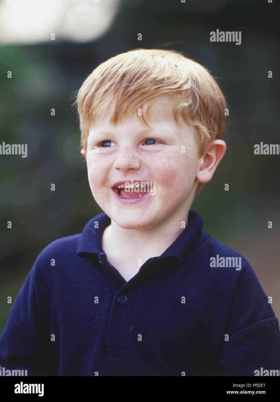 Smiling ginger boy in blue shirt, front view Stock Photo Alamy