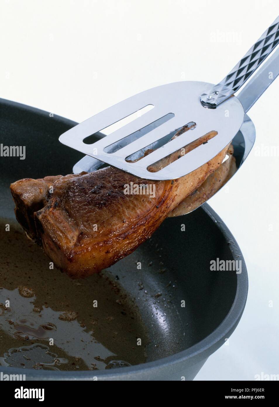 Lamb chop being lifted out of a frying pan Stock Photo - Alamy