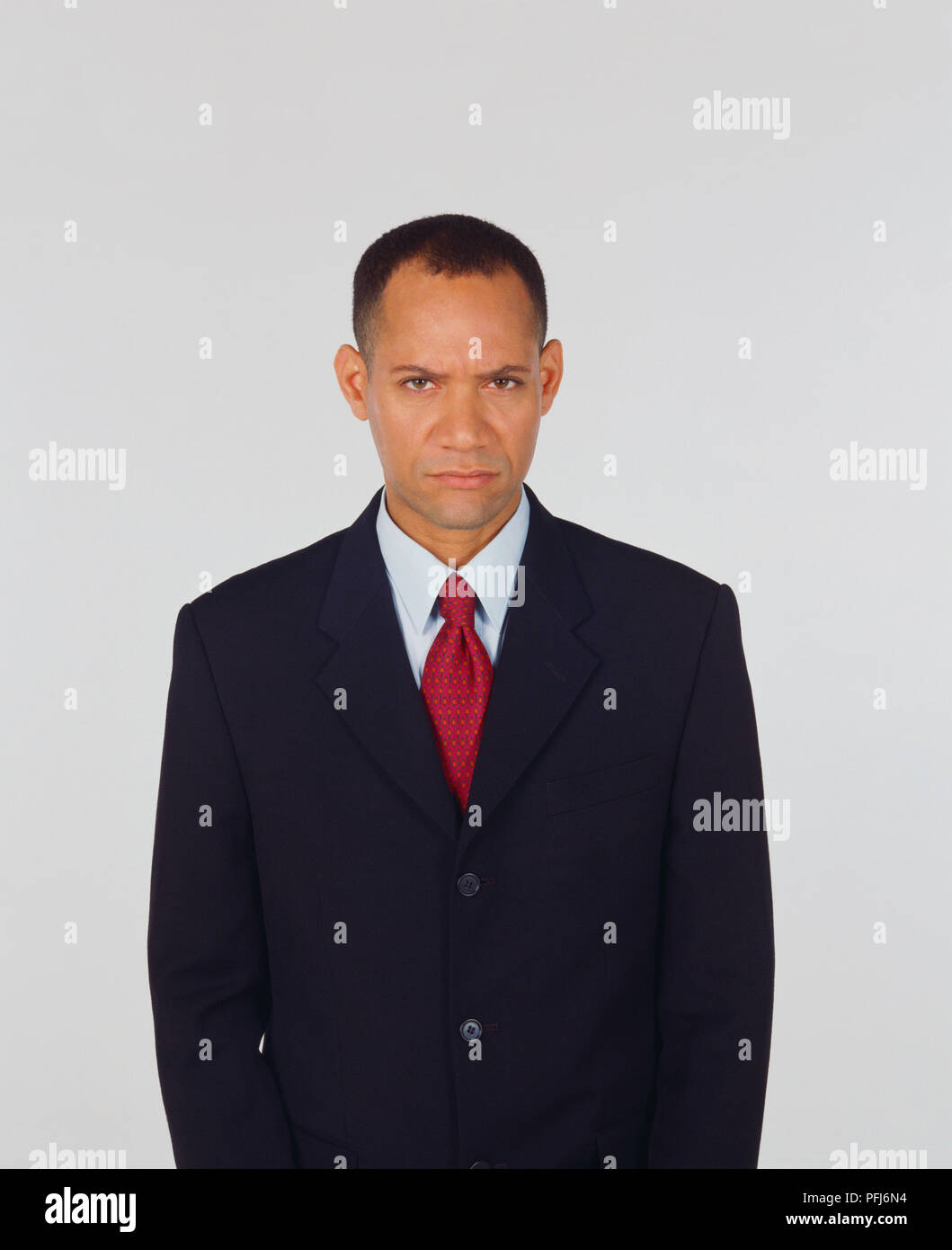 Standing man in business suit frowning, looking at camera, front view. Stock Photo
