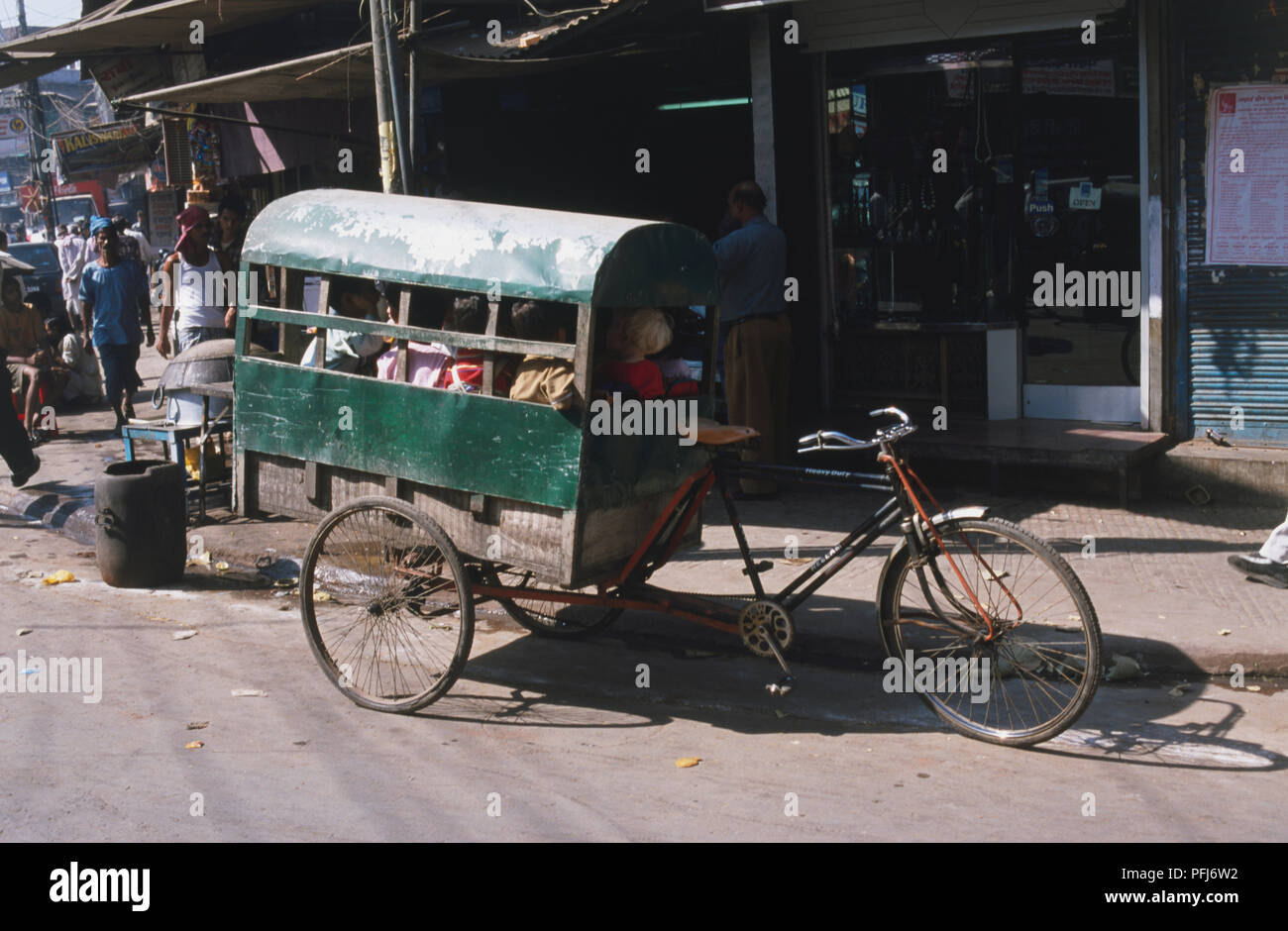 India, passengers sitting in tricycle carriage parked in street, side view. Stock Photo